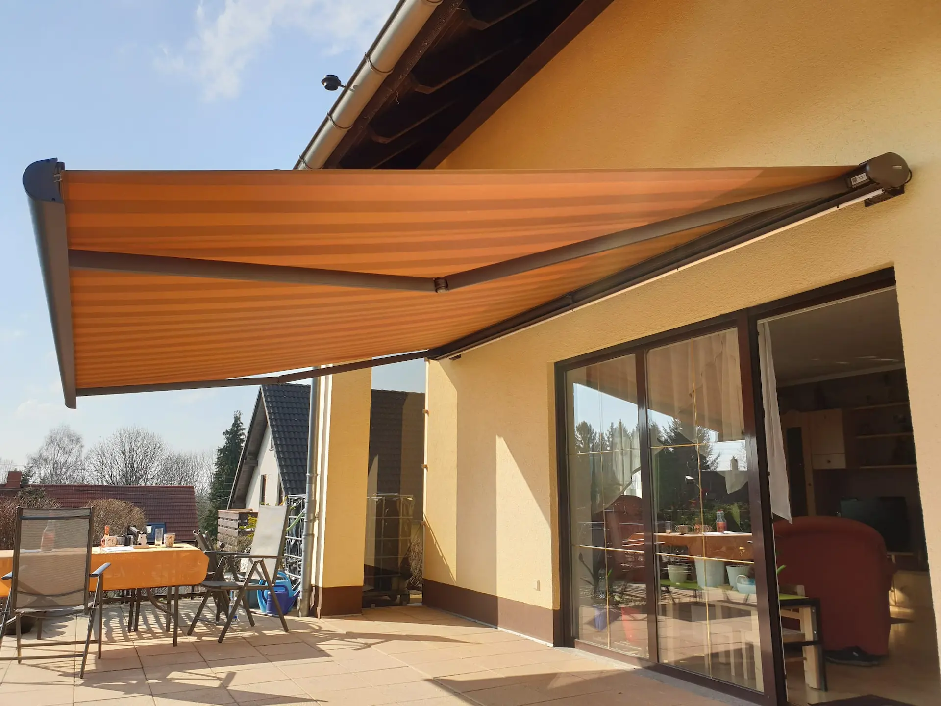 Warema Kassettenmarkise auf Terrasse bei Sonnenschein mit integrierter dimmbarer LED-Beleuchtung für modernen Sonnenschutz